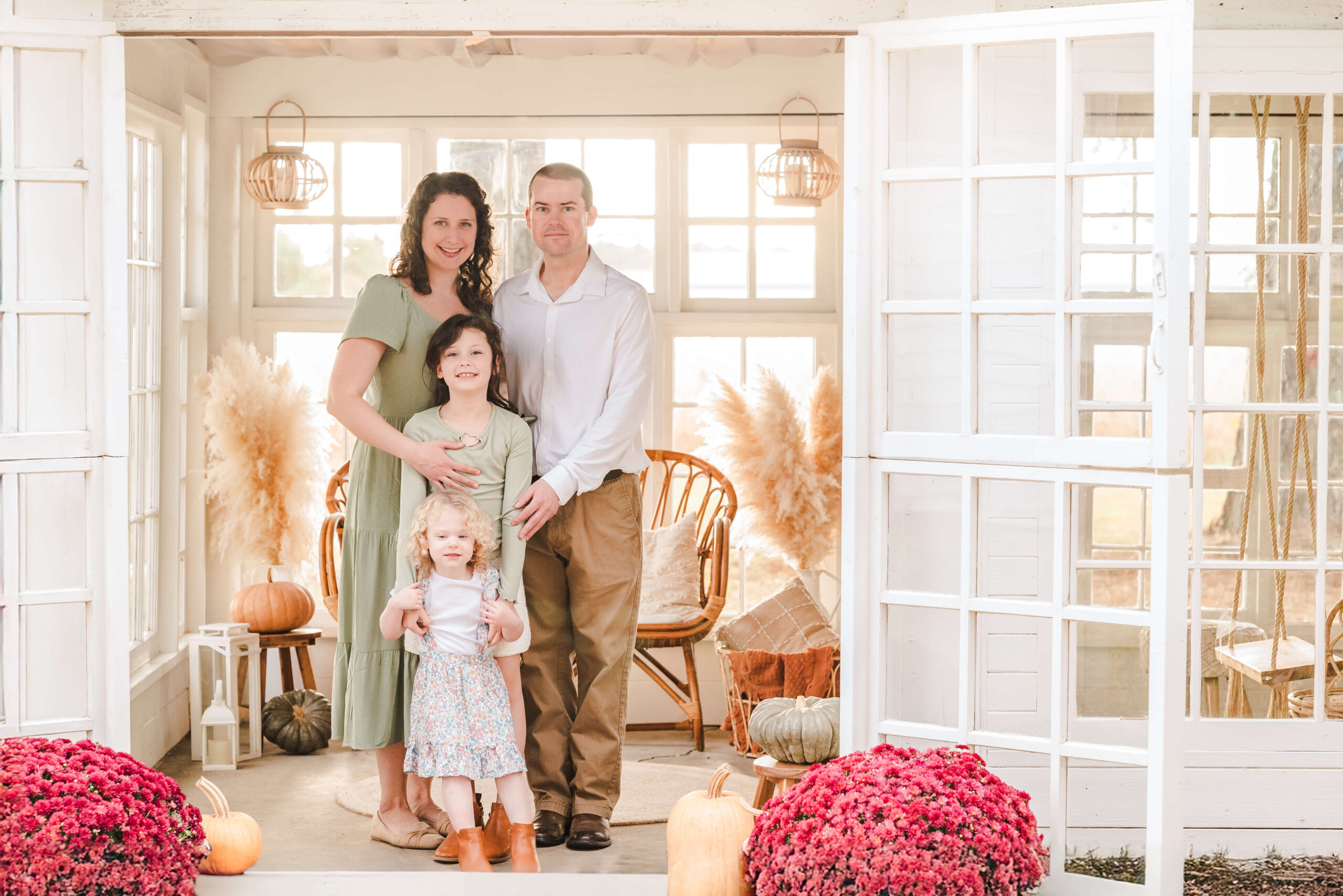 A family of four enjoys their Chesapeake autumn session at a sun porch venue. They are dressed in sage greens and whites for the season.