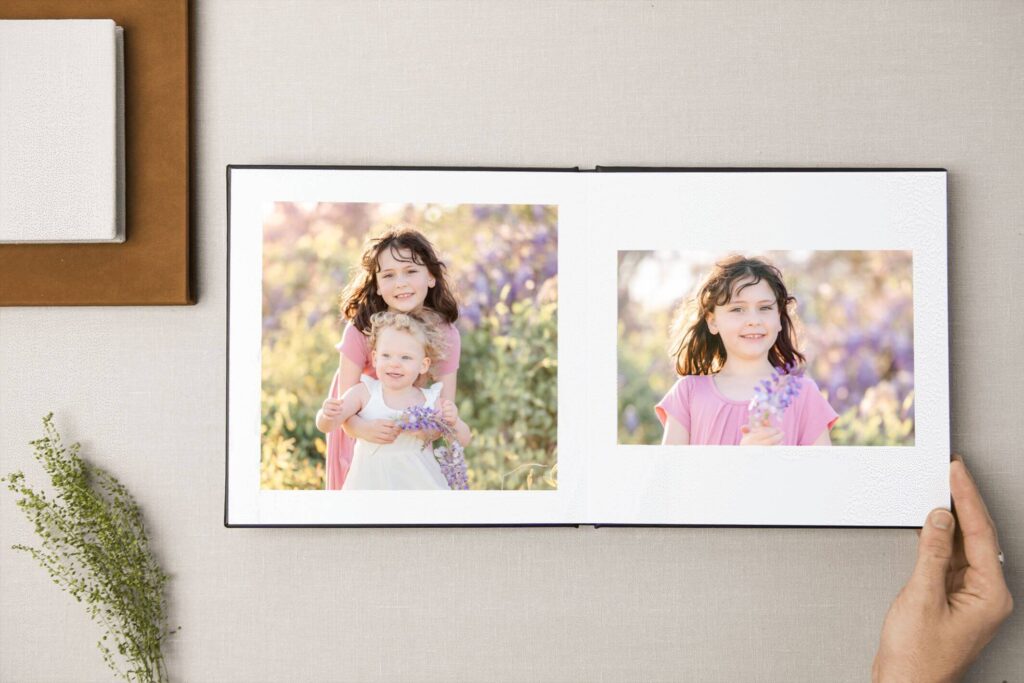 A photo album open and featuring two young girls posing near a wisteria bush. Photo albums are a great way to turn family photos into gifts.